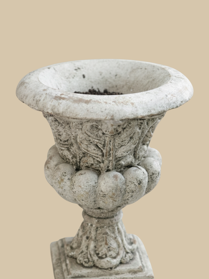 Homestyle Collective Danna Garden Urn in weathered grey concrete with ornate classical detailing for outdoor patios.