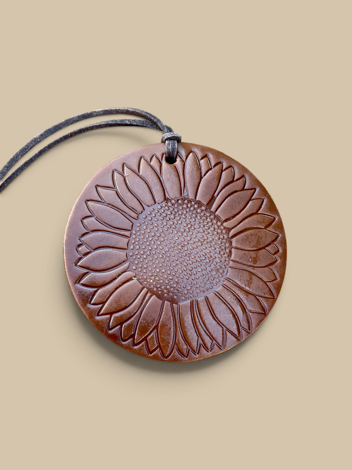 Homestyle Collective leather air freshener with a sunflower design, featuring a rich brown finish and leather cord.
