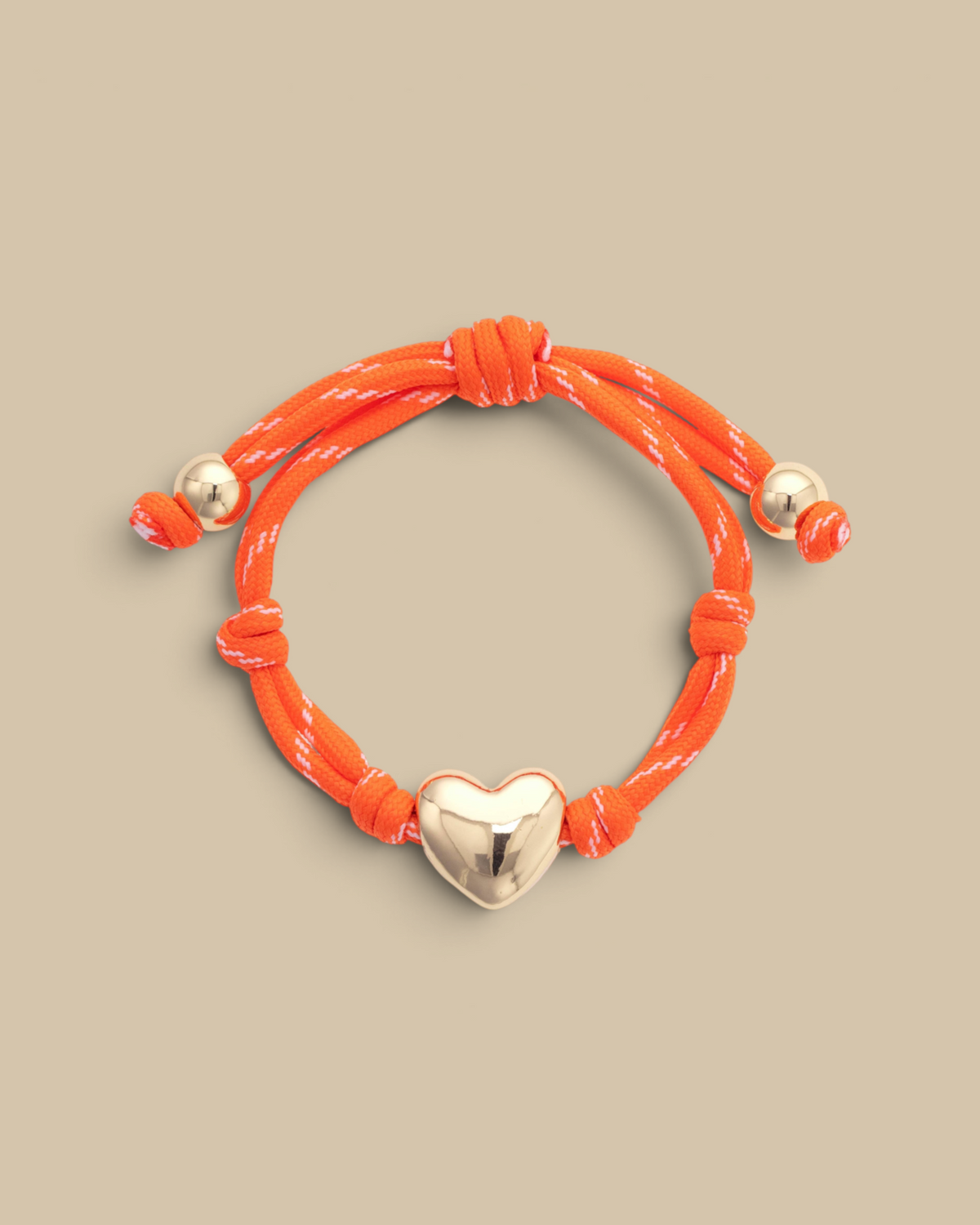 Homestyle Collective orange paracord bracelet featuring a glossy gold puffy heart charm and adjustable knot details.