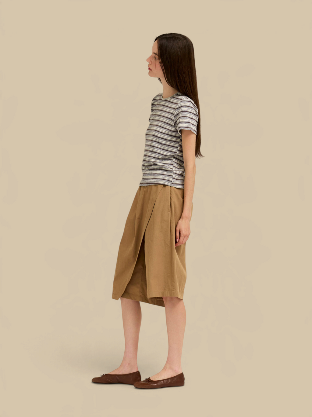 Homestyle Collective stripe jersey tee in light grey worn with a tan wrap skirt and brown flats by a female model.
