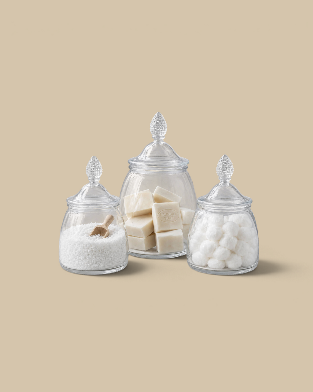 Homestyle Collective glass teardrop jars in three sizes filled with laundry soap, salt, and cotton balls on marble.