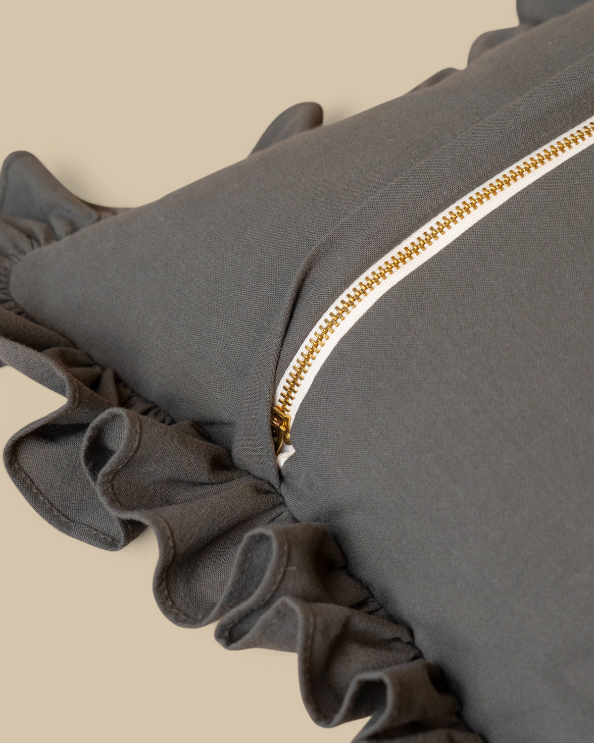 Homestyle Collective green sand-wash cotton lumbar pillow cover with ruffled edges and a brass zipper back closure.