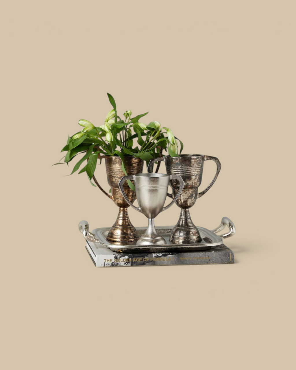 Homestyle Collective distressed metal trophy cups in gold and silver arranged on a tray with flowers