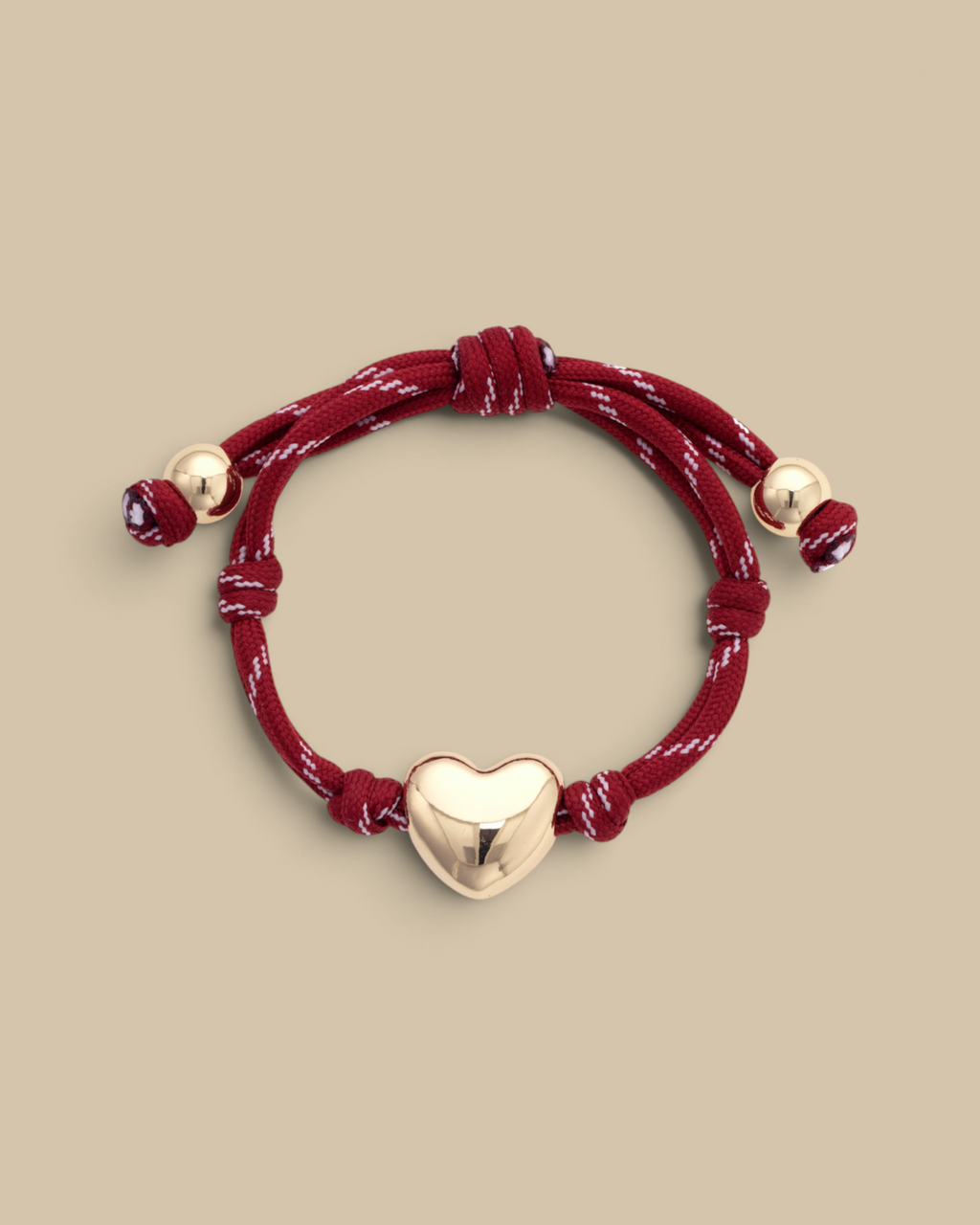 Homestyle Collective red paracord bracelet featuring a glossy gold puffy heart charm and adjustable knot closure.