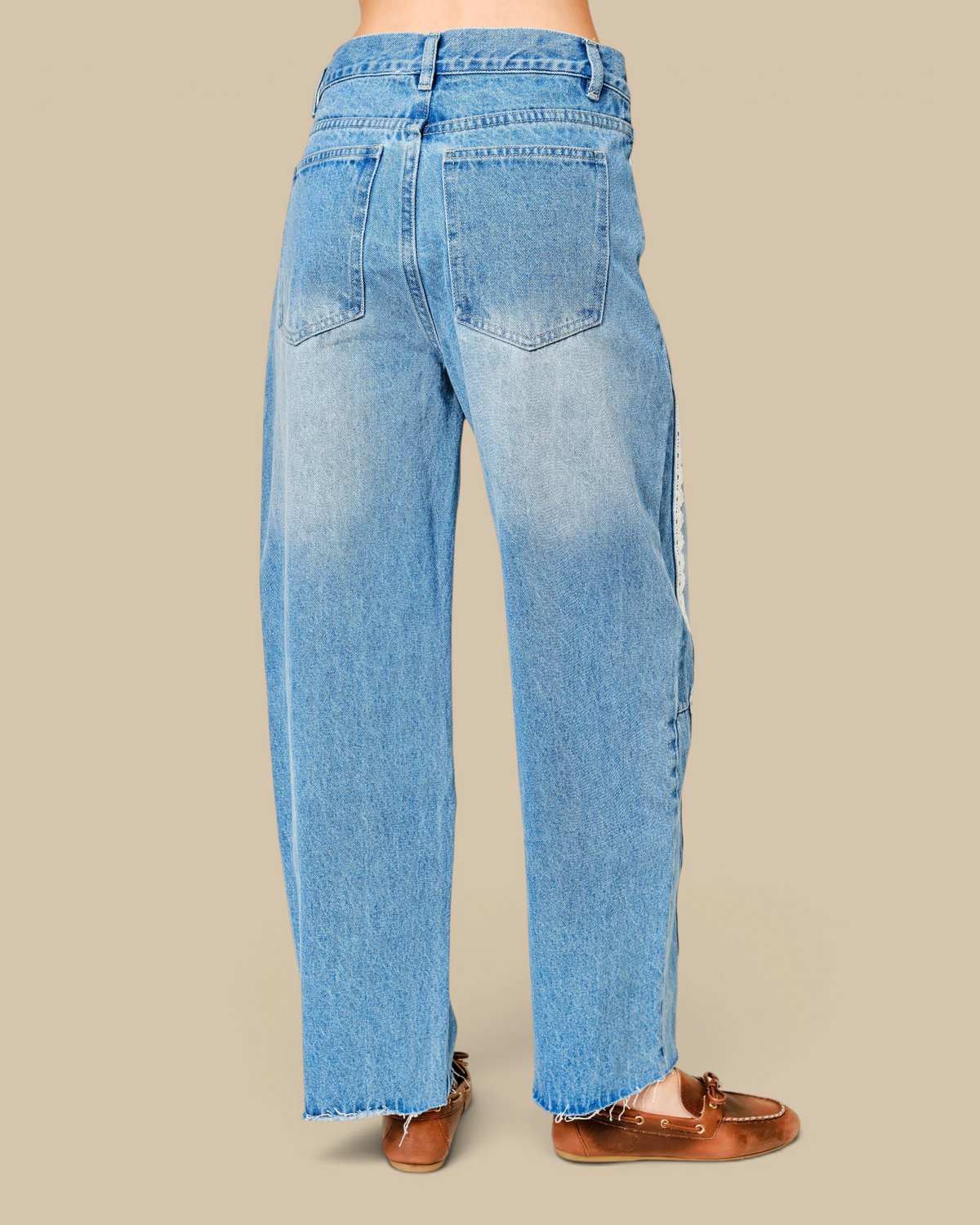 Homestyle Collective light wash barrel leg denim jeans featuring delicate white lace side trim and raw hem back view