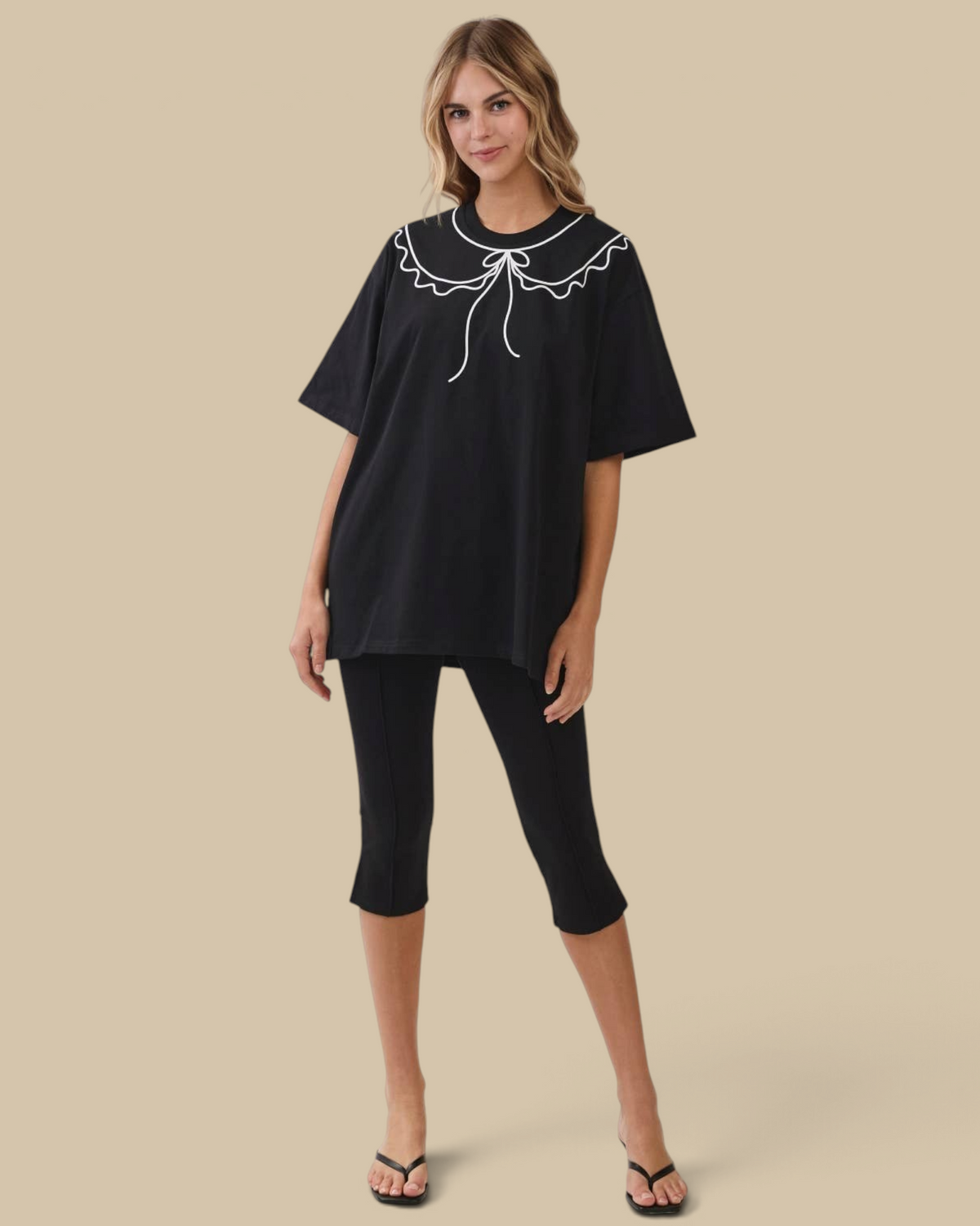 Model wearing a Homestyle Collective black oversized cotton tunic tee with a white scalloped collar and tie detail.