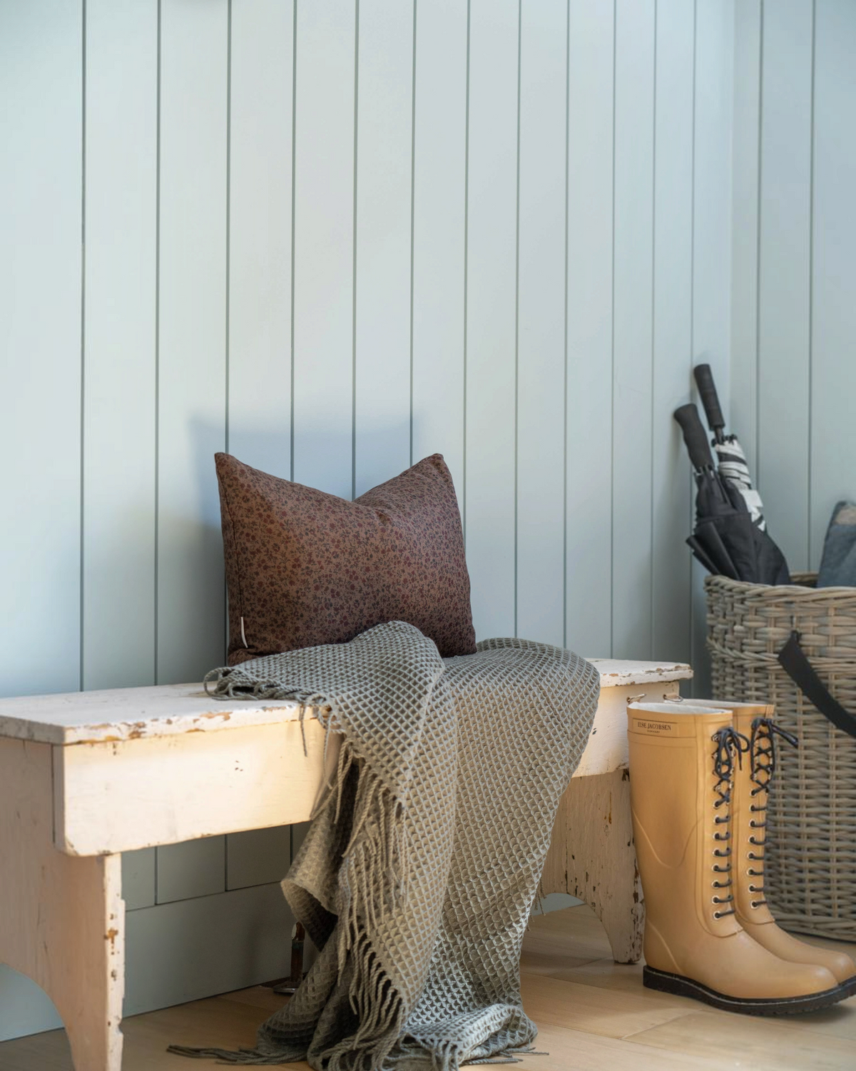 Homestyle Collective Trudie floral linen pillow cover in brown and burgundy on a rustic bench with a waffle throw.