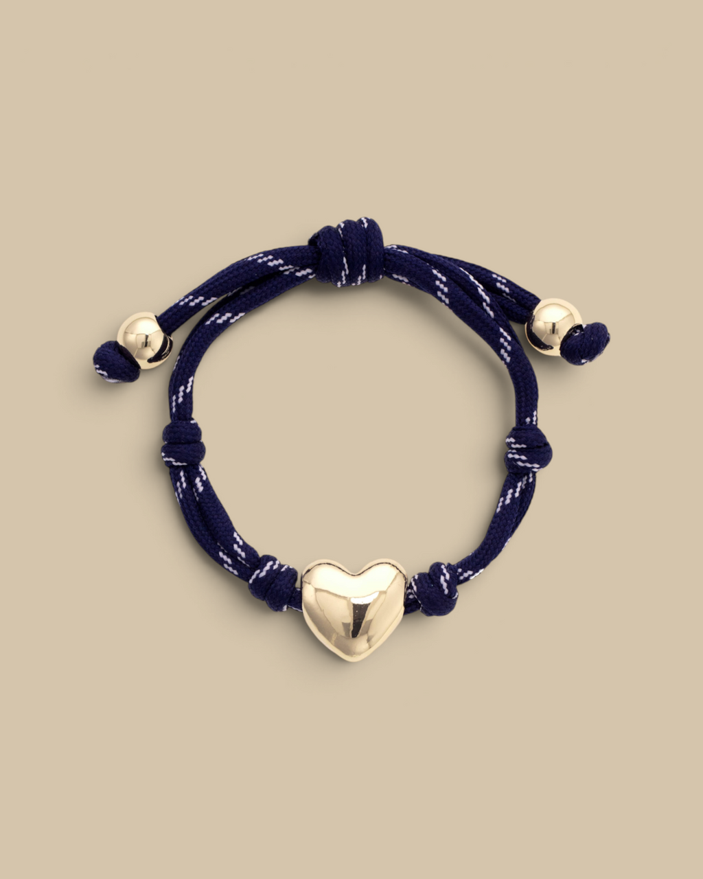 Homestyle Collective navy blue paracord bracelet featuring a glossy gold puffy heart charm and adjustable knot design.