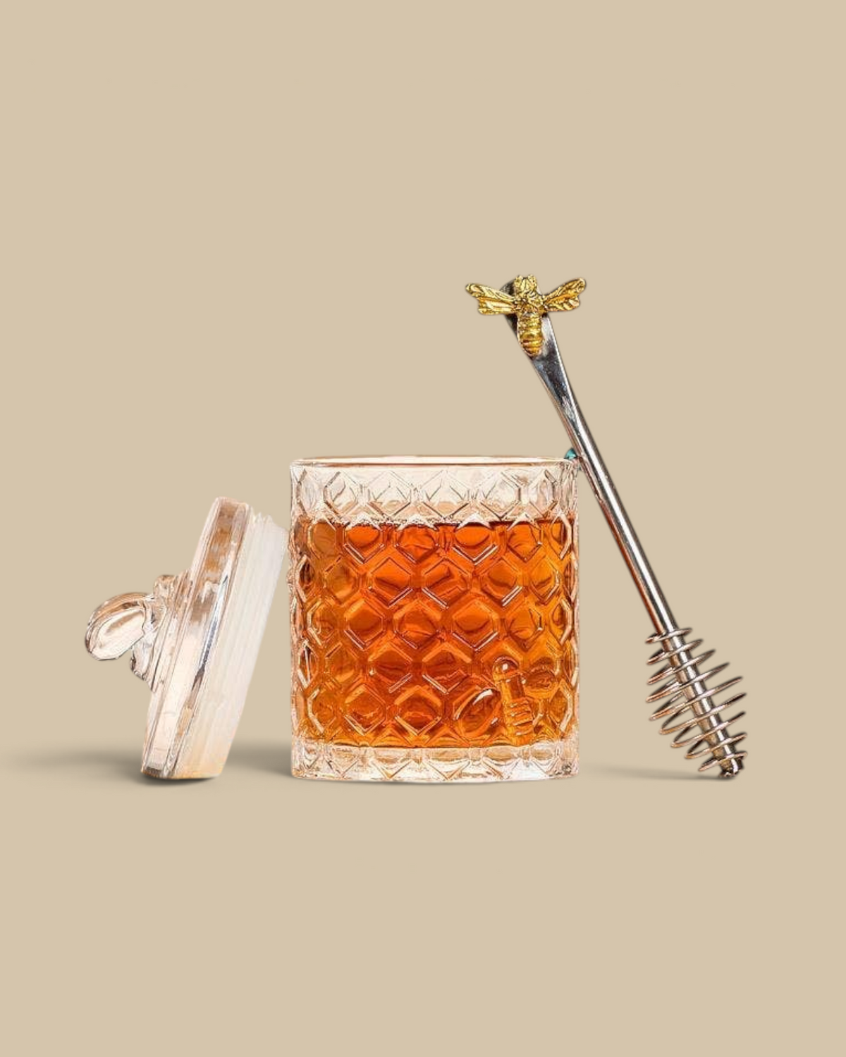 Homestyle Collective honeycomb glass jar with bee lid and metal honey dipper on a yellow checkered cloth