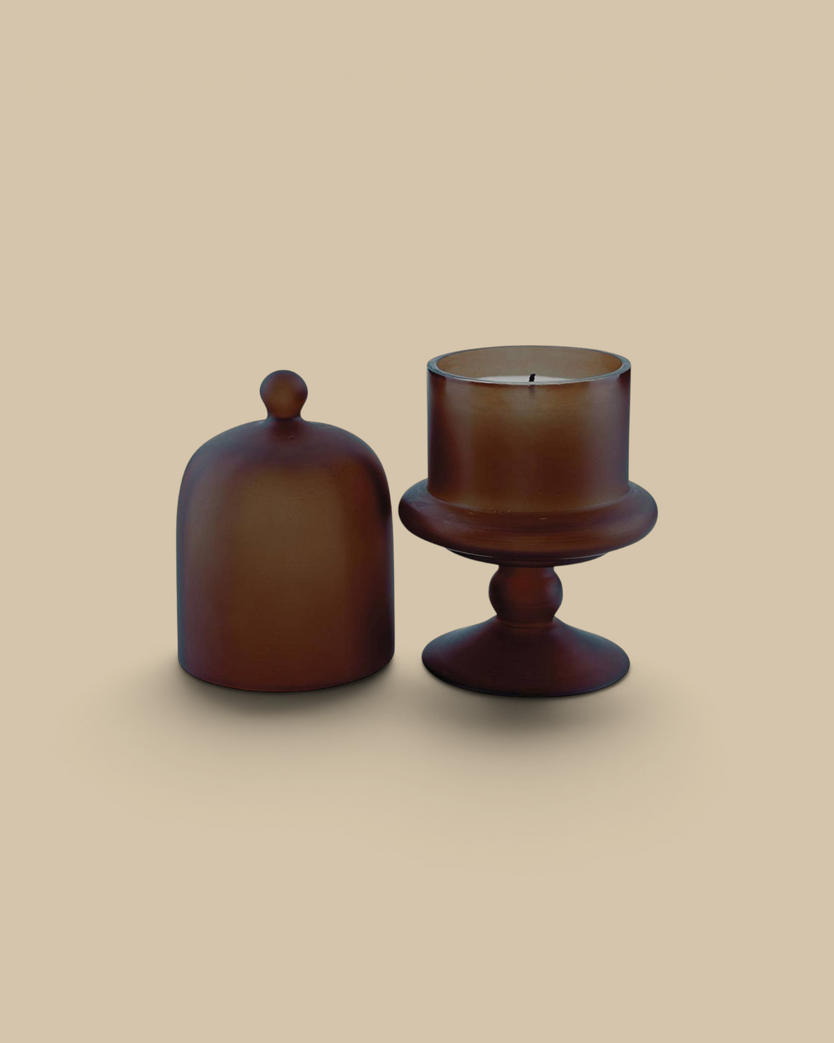 Homestyle Collective brown cloche candle in a smoky amber glass bell jar with a pedestal base and removable lid.