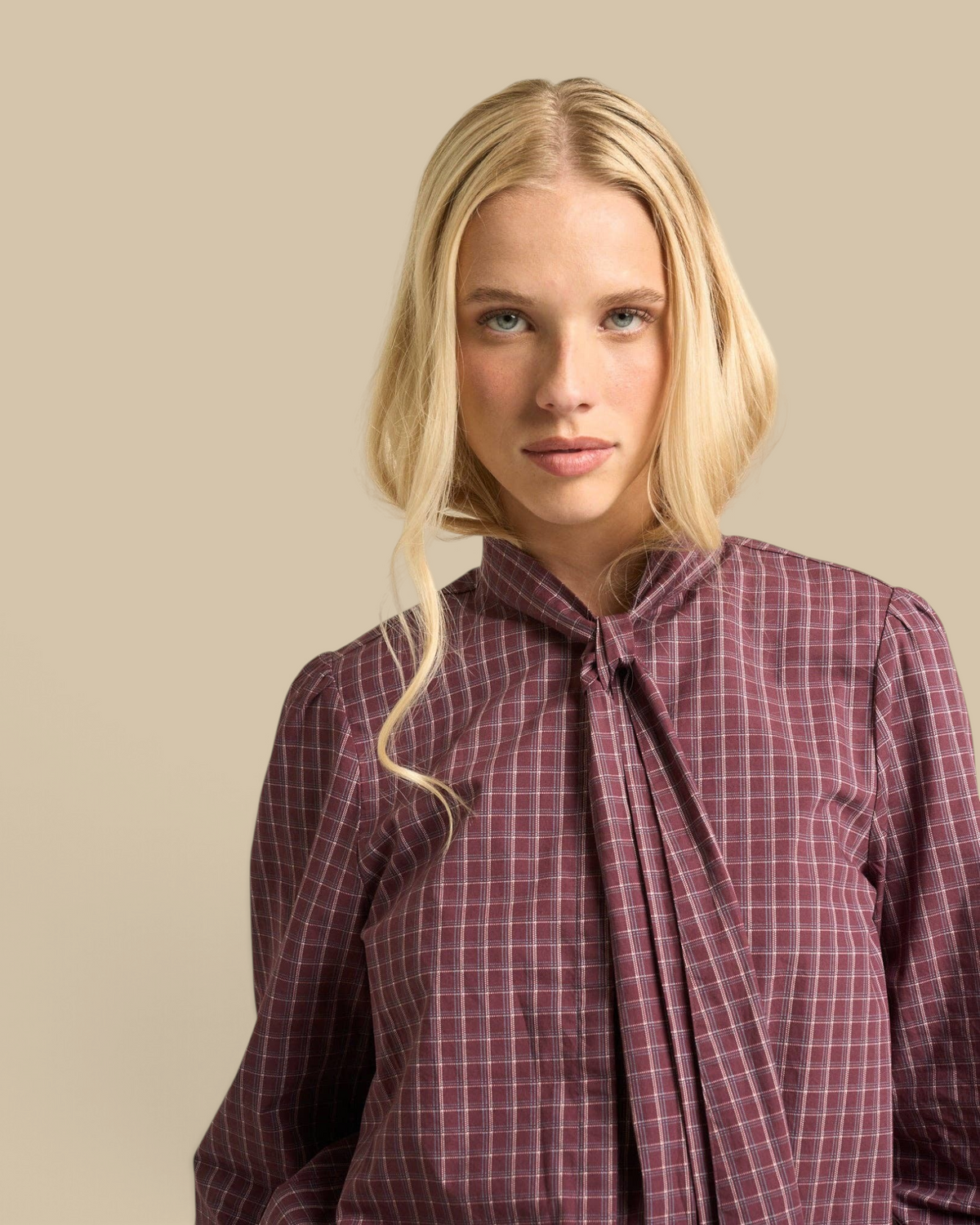 Homestyle Collective Lily Blouse in burgundy cotton gingham with a tie-neck detail worn by a blonde model.