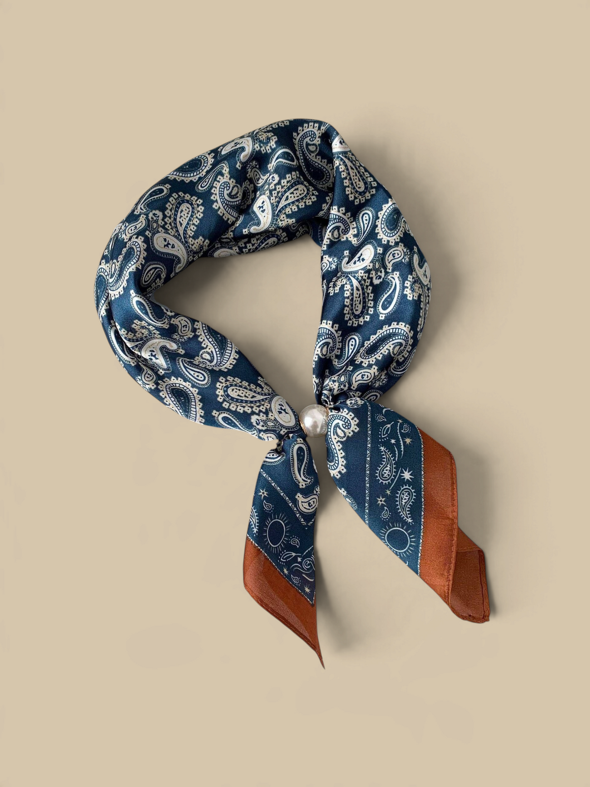 Homestyle Collective navy paisley silk neckerchief scarf with a sleek magnetic pearl closure on a display tray