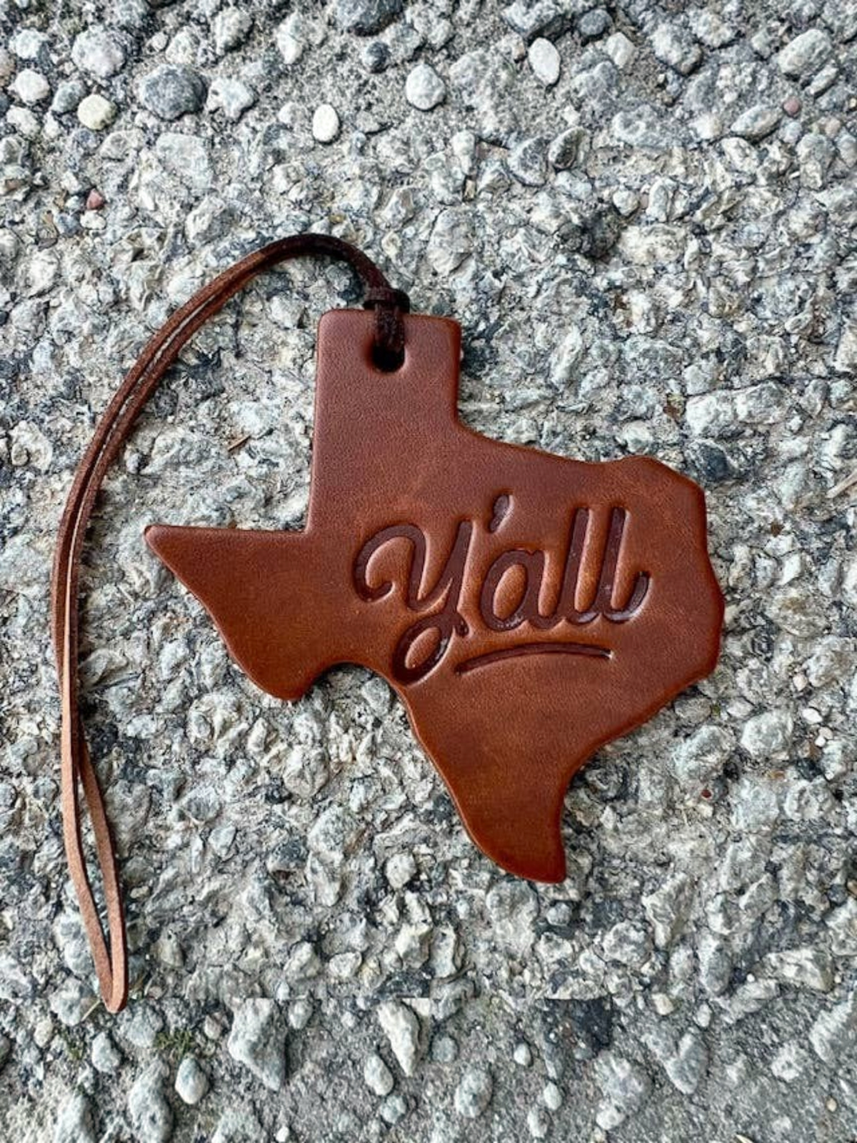 Homestyle Collective Texas-shaped leather air freshener with y'all embossed, featuring a brown leather hanging cord.