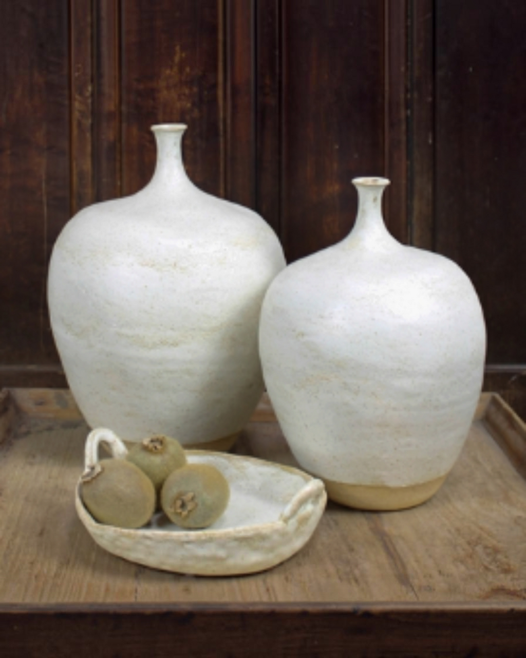 Homestyle Collective Wabi ceramic handled platter with organic texture holding fruit next to two white vases.