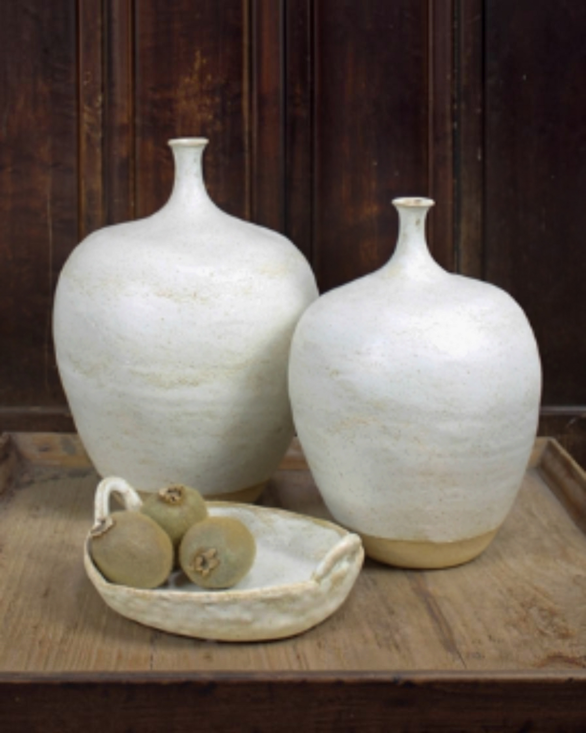 Homestyle Collective Wabi ceramic handled platter with organic texture holding fruit next to two white vases.
