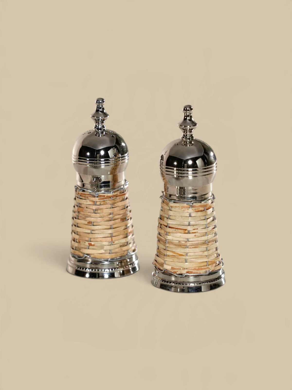 Homestyle Collective Cap Ferrat salt and pepper shakers with polished metal tops and handwoven natural rattan bases.