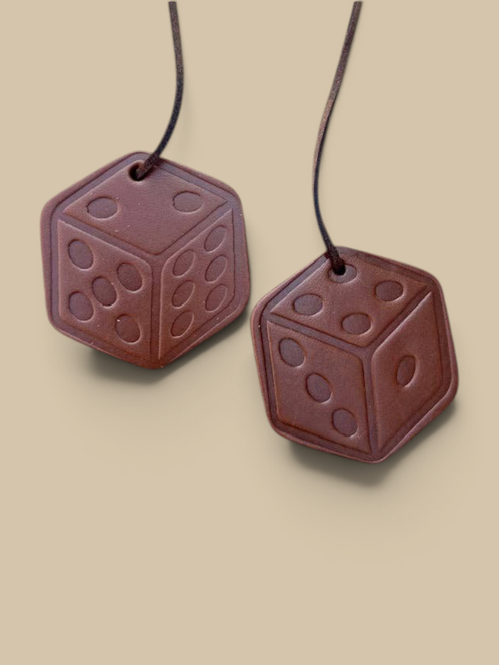 Homestyle Collective leather scented air freshener dice with brown leather cord on a stone background
