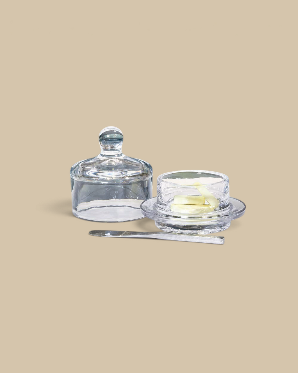 Homestyle Collective small glass butter dish with a matching dome lid and a silver butter knife on a white table