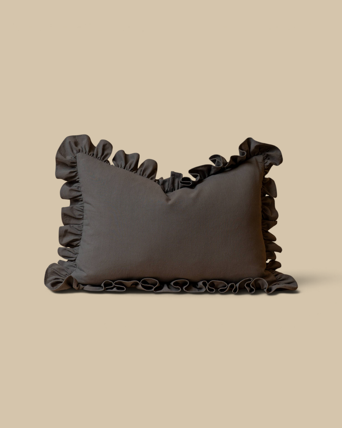 Homestyle Collective green sand-wash cotton lumbar pillow cover with decorative ruffled edges on a tan background