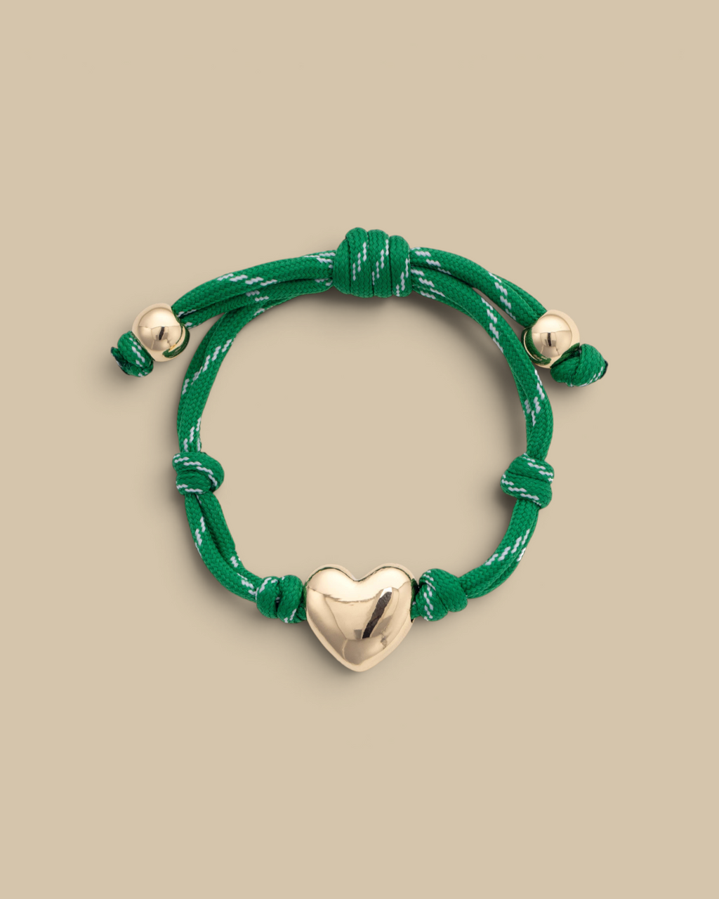 Homestyle Collective green paracord bracelet featuring a glossy gold puffy heart charm and adjustable knot design.