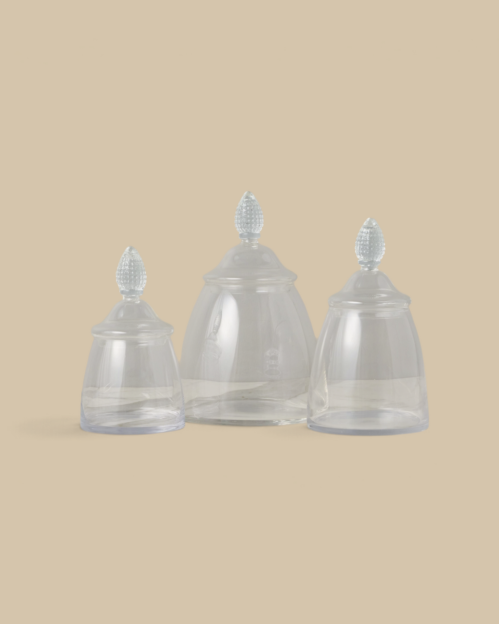 Homestyle Collective glass teardrop jars in three sizes with textured finials displayed on a marble surface.