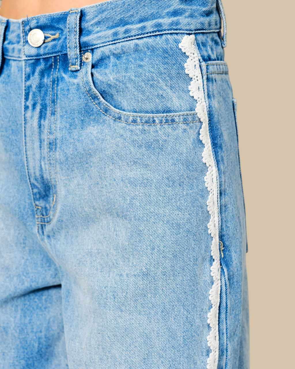 Homestyle Collective light wash denim jeans featuring a relaxed barrel silhouette and delicate white lace side trim.