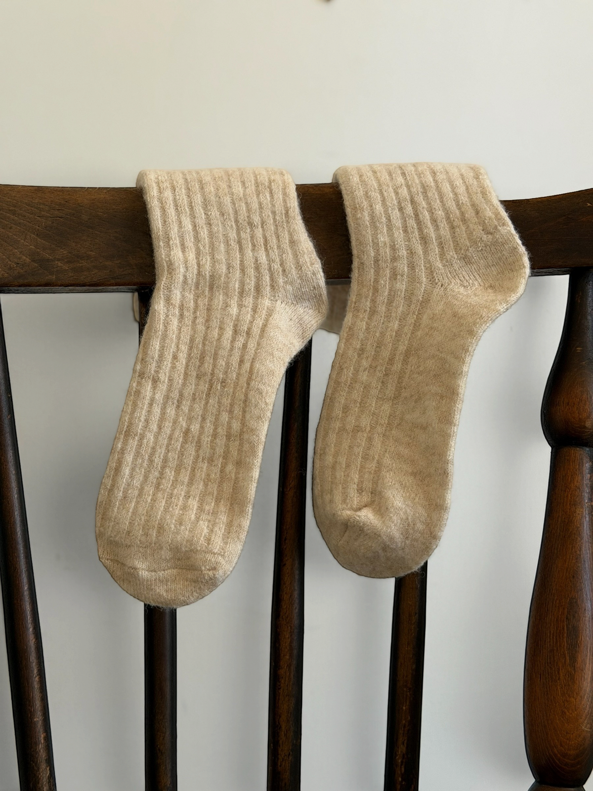 Homestyle Collective plush apricot wool crew socks with a ribbed texture draped over a wooden chair