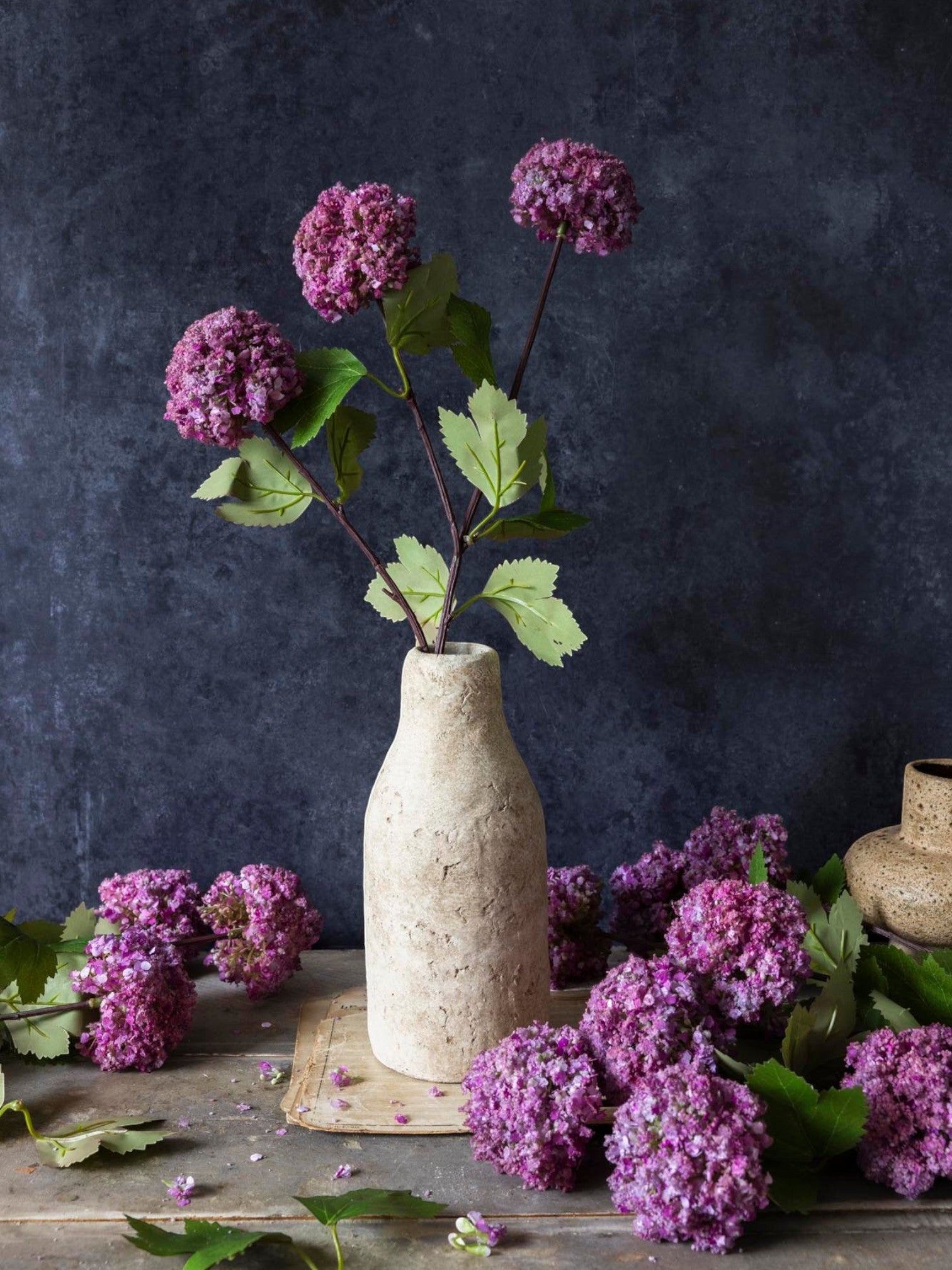 Homestyle Collective artificial mauve Guelder Rose stem with abundant flower heads and green leaves in a textured vase.