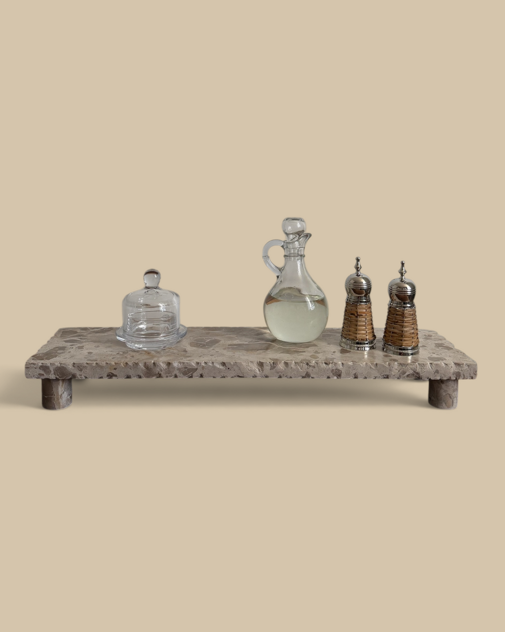 Homestyle Collective beige marble pedestal stand with natural veining displaying glass kitchen accessories on a table