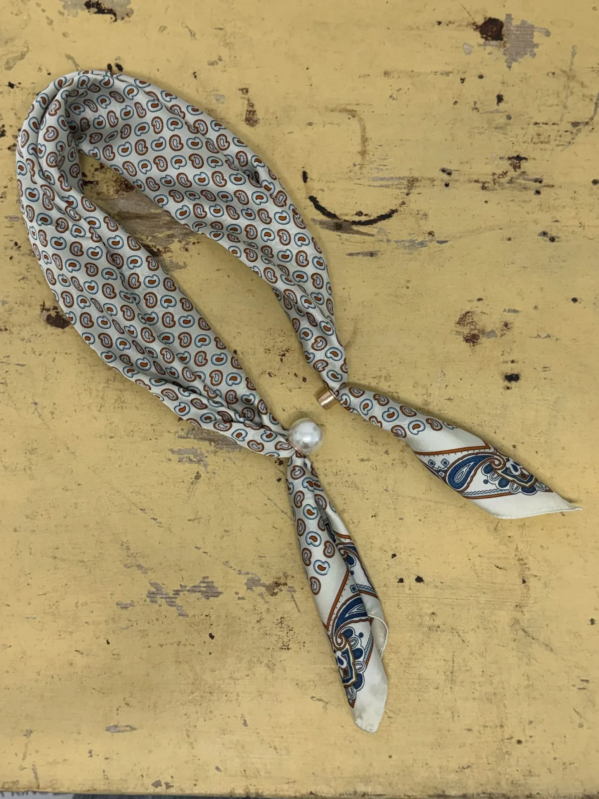 Homestyle Collective beige mini paisley silk neckerchief scarf with a sleek magnetic pearl closure.