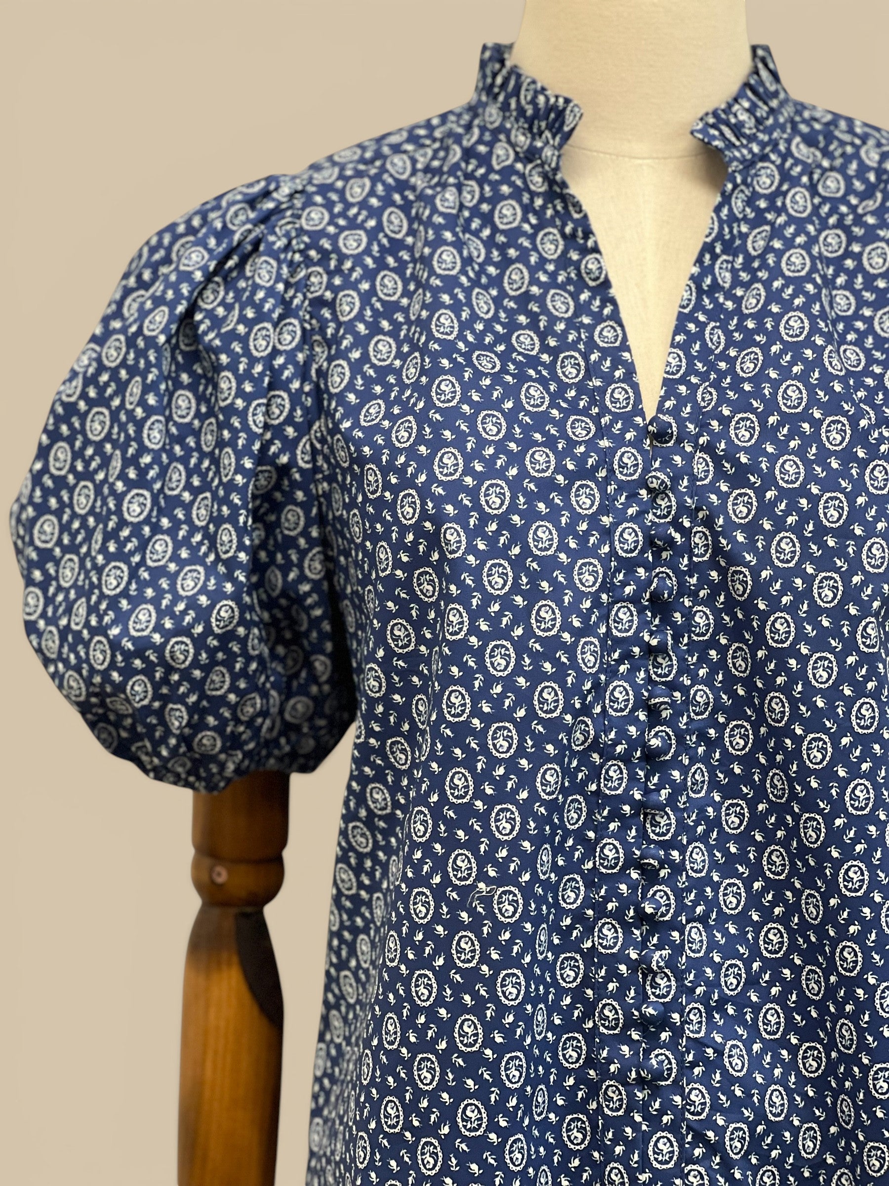 Homestyle Collective blue floral cameo blouse with ruffled neckline, V-neck, and balloon sleeves.