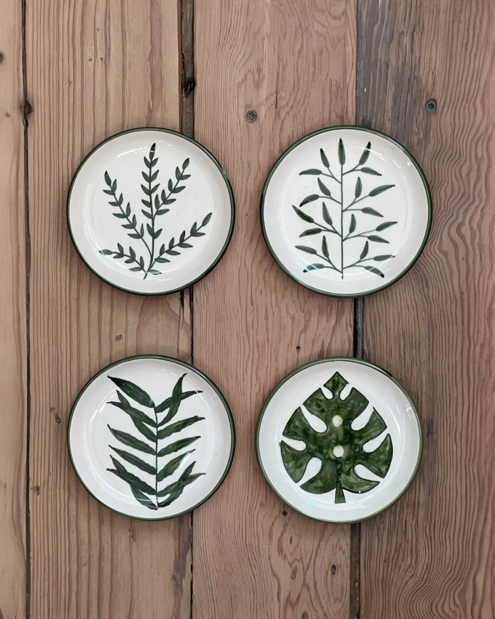 Homestyle Collective botanical stoneware plates feature hand-painted dark green leaf designs on a cream background with a dark green rim.