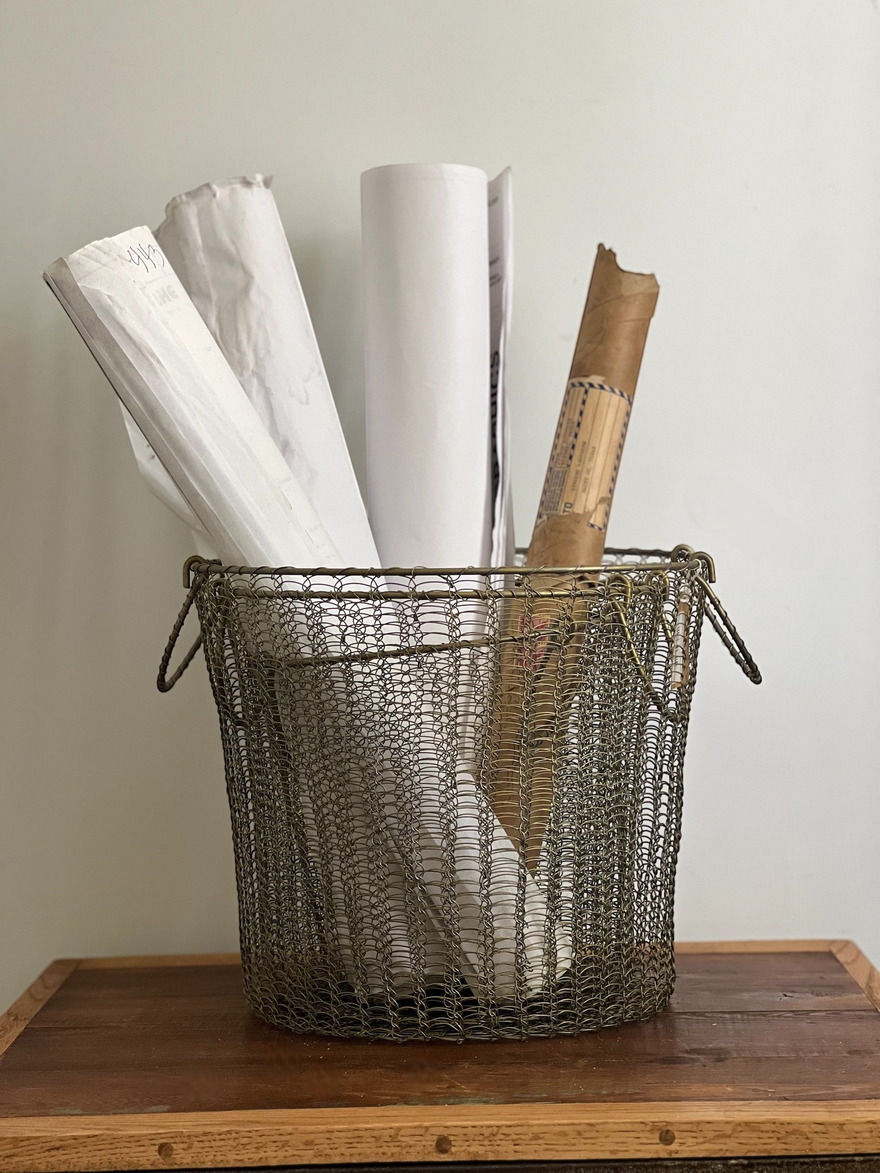 Homestyle Collective Moana brass wire basket with handles, holding rolled papers and documents. Set of 3.