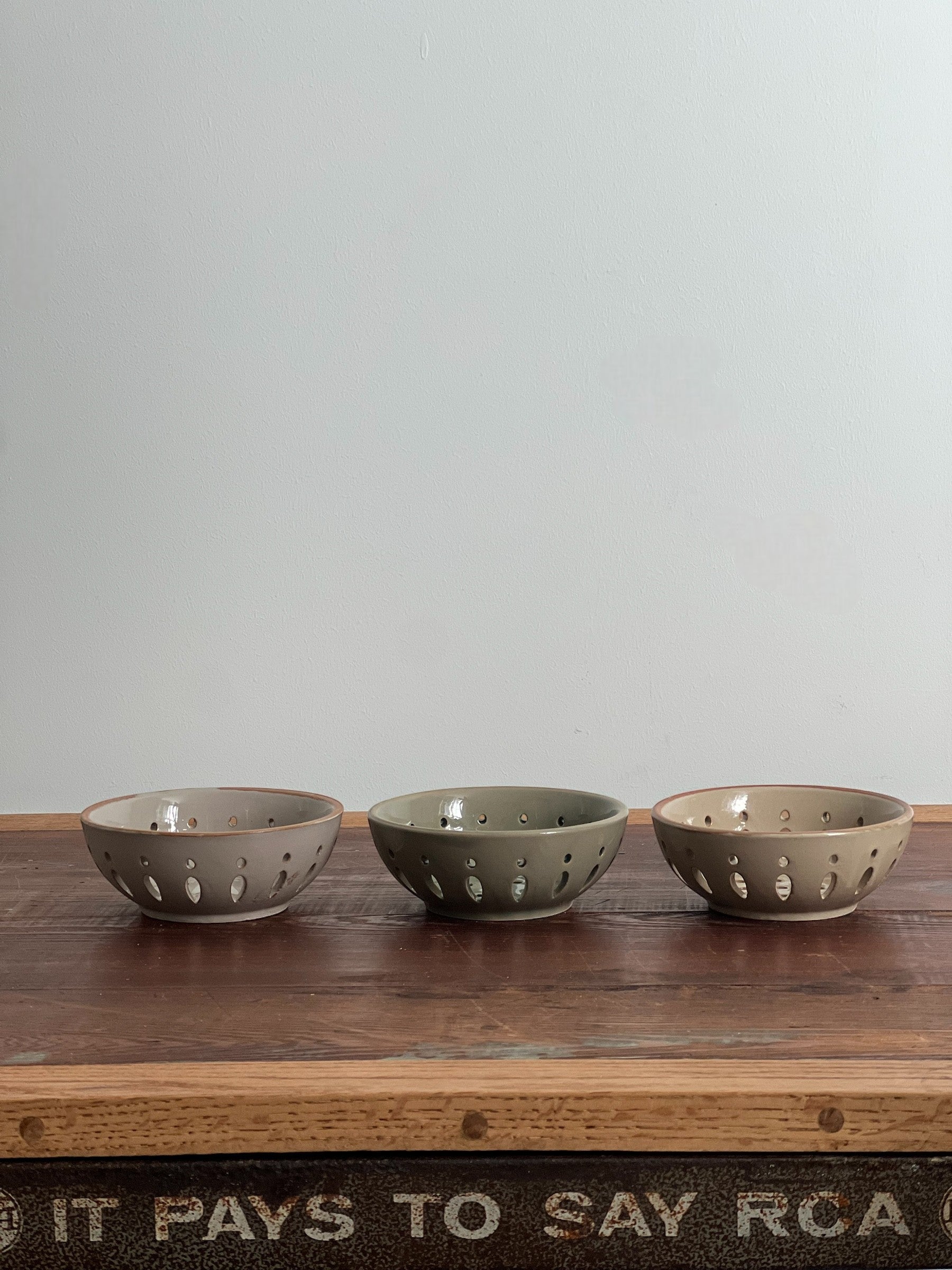 Homestyle Collective three ceramic bowls in cream, sand, and green/grey with drainage holes for serving fruit.