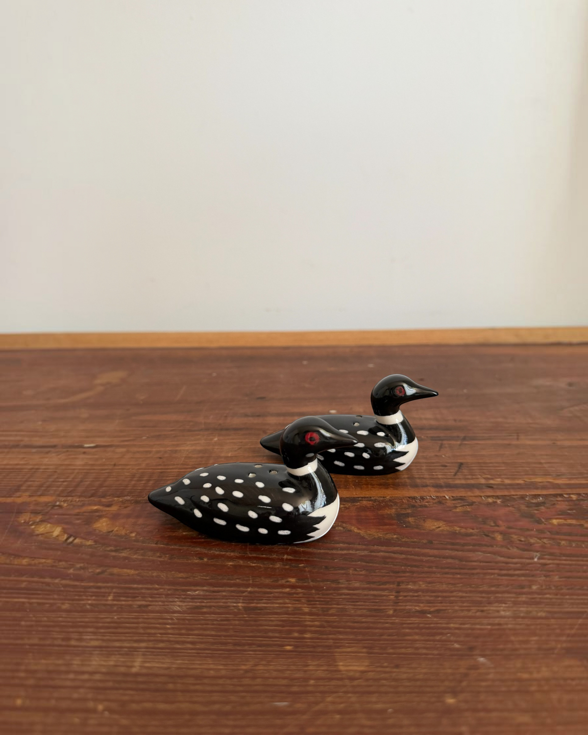 Homestyle Collective ceramic loon salt and pepper shakers with black and white spotted pattern on a wooden table.