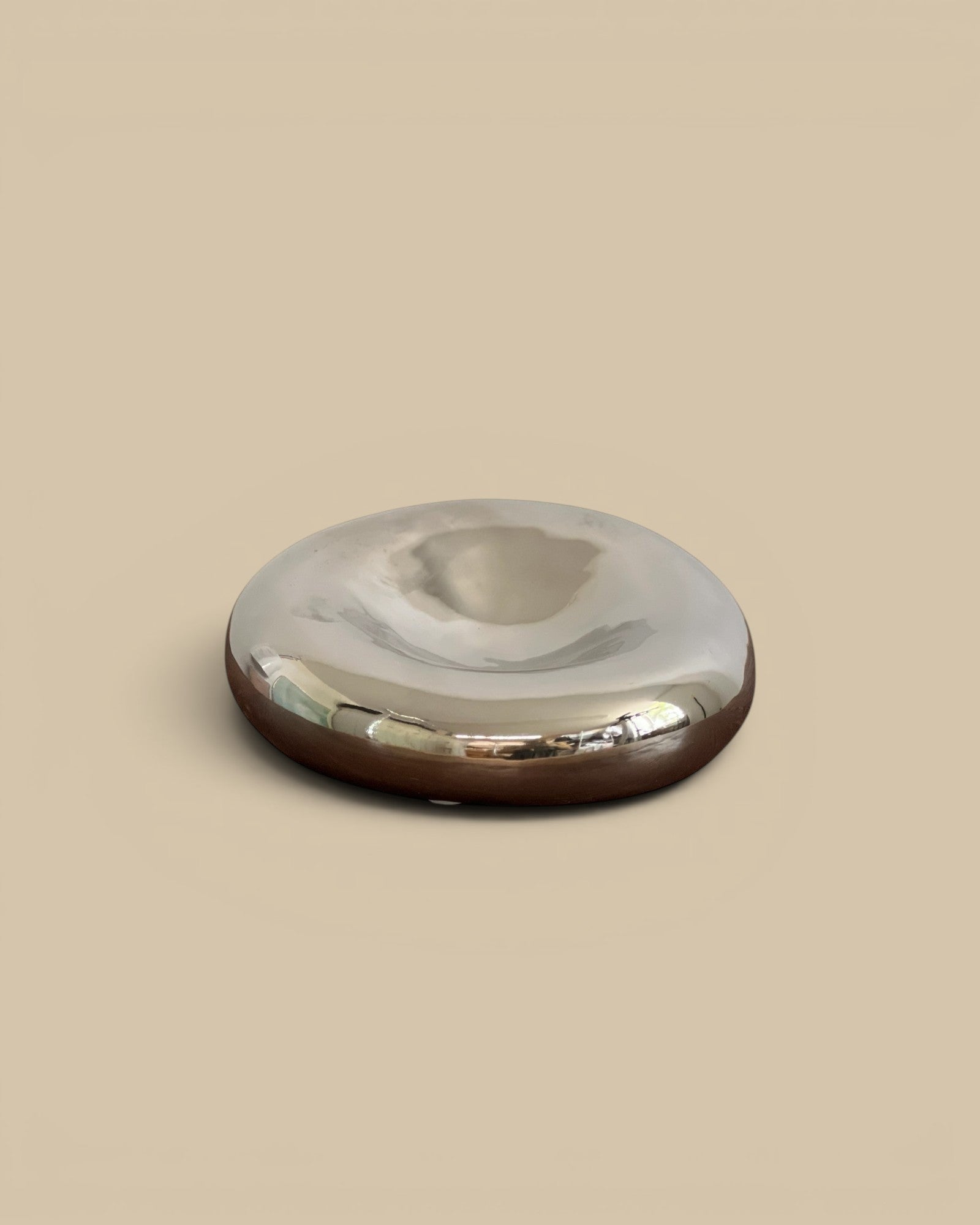 Homestyle Collective chrome glazed decorative bowl with a smooth, reflective surface and a dark base.