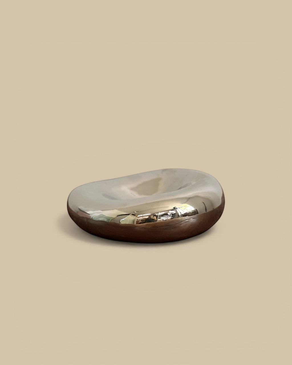Homestyle Collective chrome glazed abstract object with a smooth, reflective surface and a dark base.