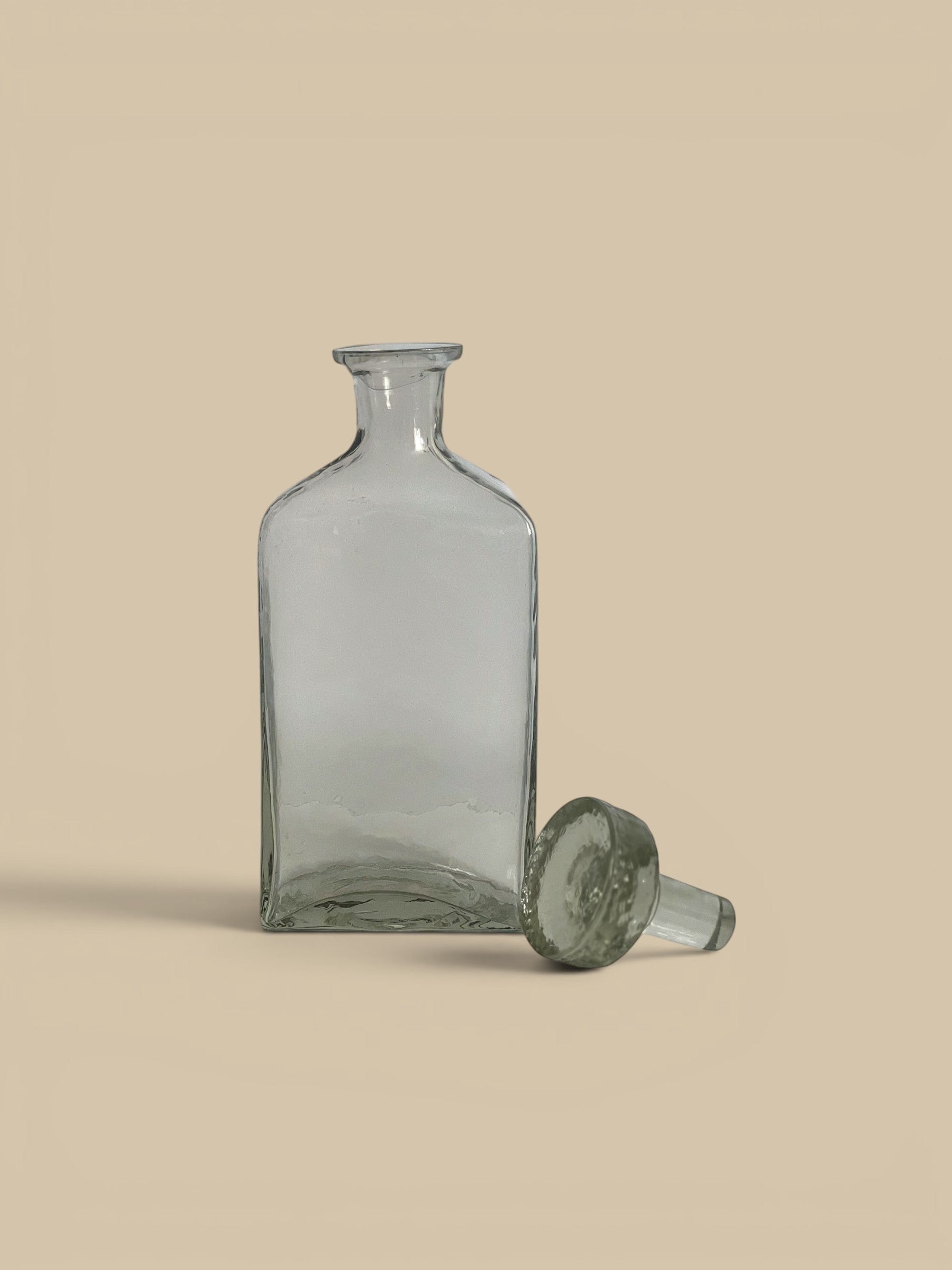 Homestyle Collective clear glass decanter with a minimalist silhouette and stopper. Ideal for spirits or decorative use.