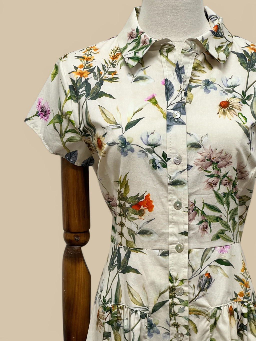 Homestyle Collective Collette Dress, a cream shirt dress with a vibrant floral print, short sleeves, and button front.