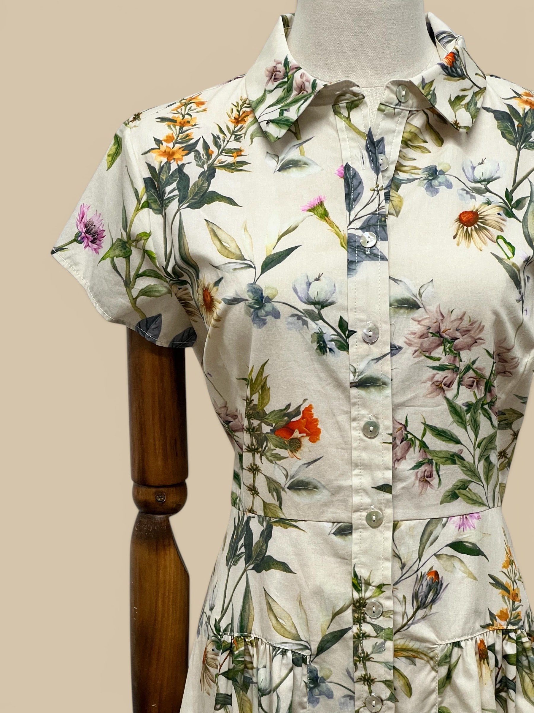 Homestyle Collective Collette Dress, a cream shirt dress with a vibrant floral print, short sleeves, and button front.