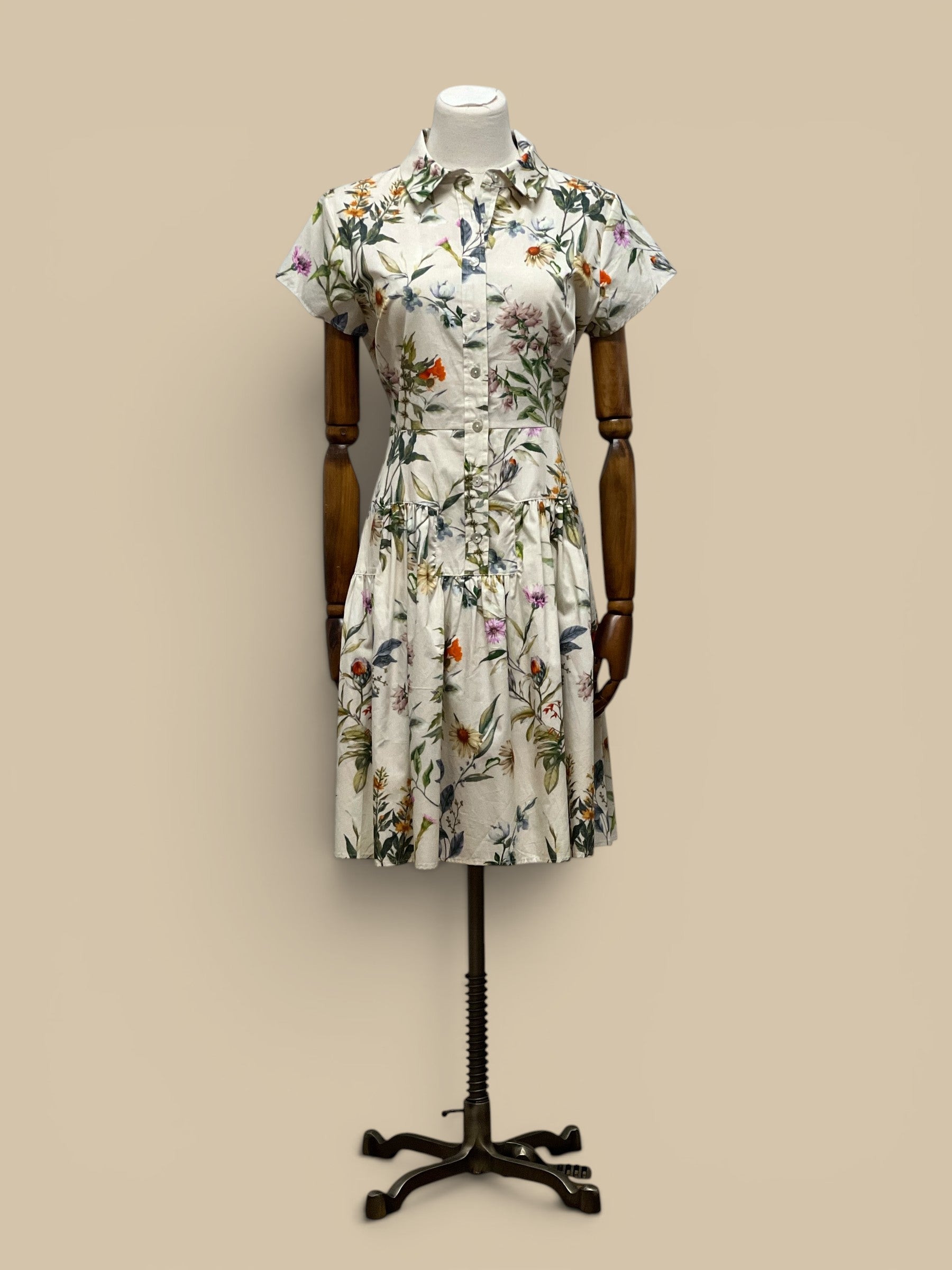Homestyle Collective Collette Dress: A short-sleeved, collared midi dress with a white base and a vibrant floral print. Features a button-down front and a tiered skirt.