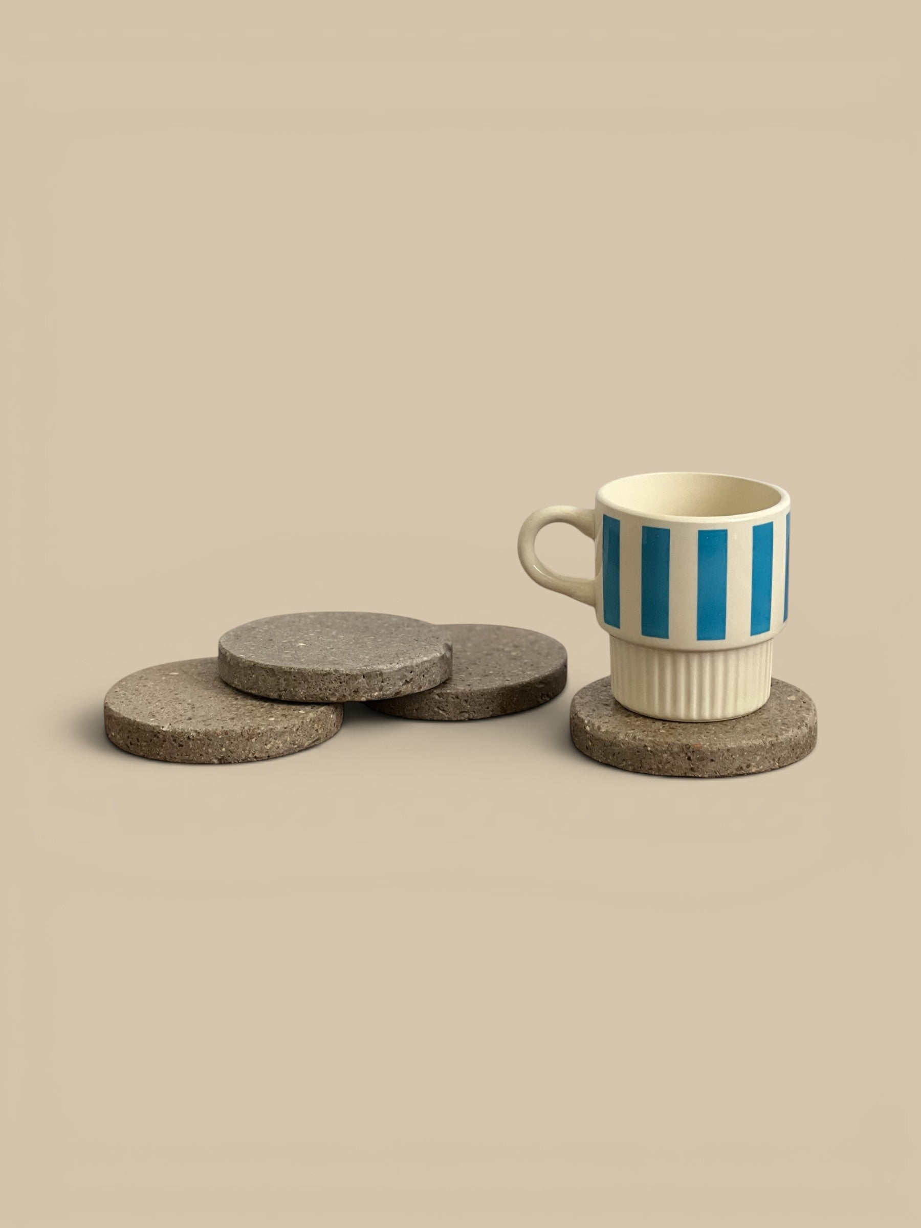 Homestyle Collective natural grey speckled concrete round coasters, set of 4, with a mug on one.