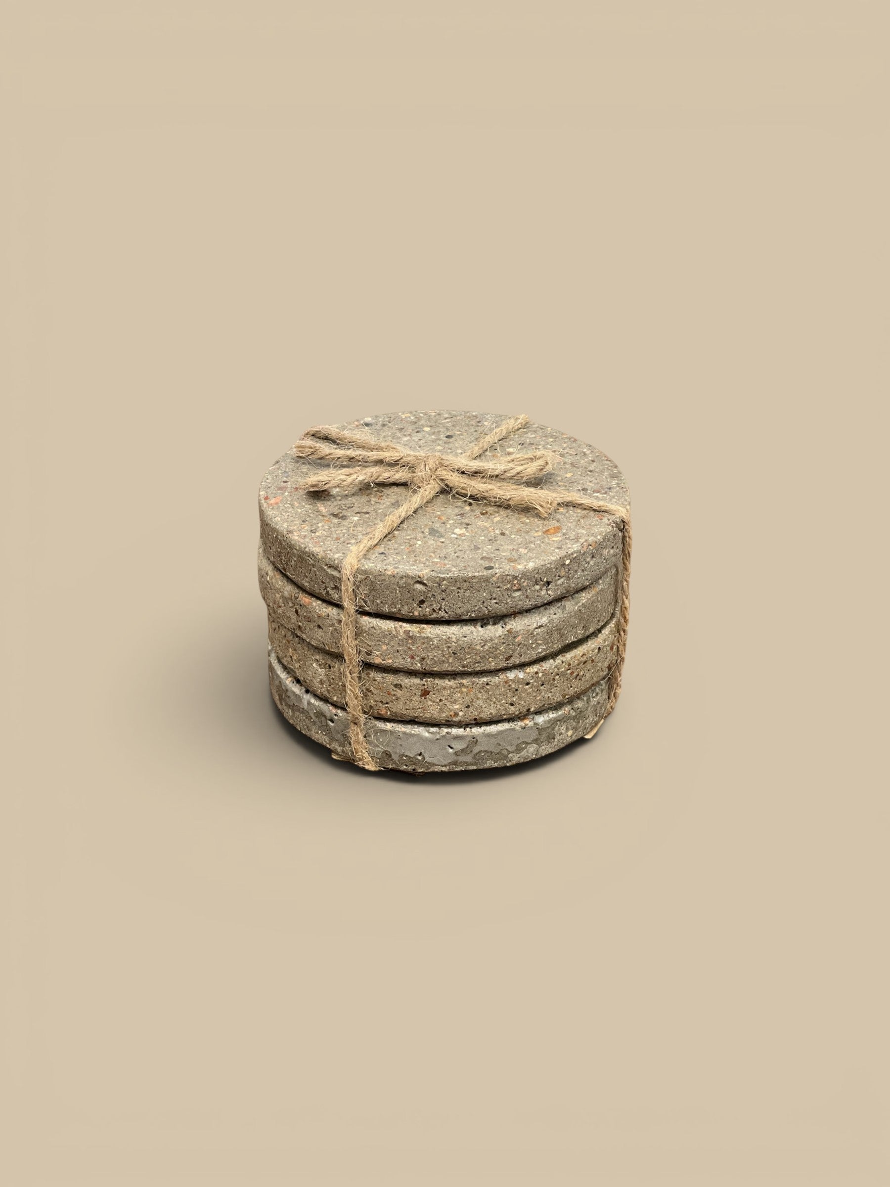 Homestyle Collective set of 4 round concrete coasters with a natural speckled finish, tied with twine.