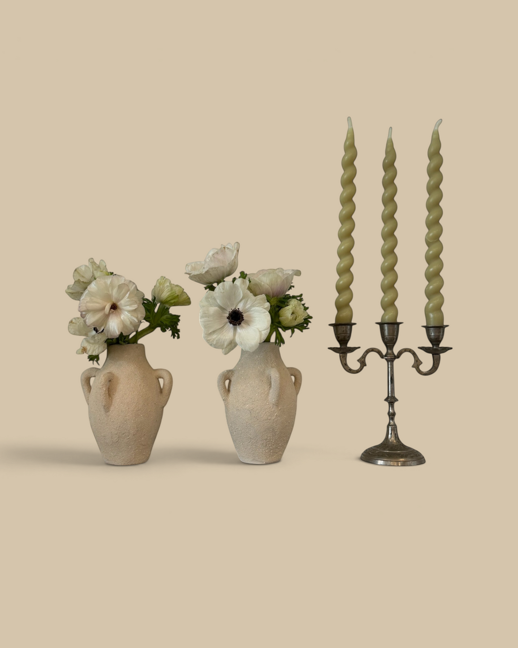 Homestyle Collective cream clay vase with four handles holding white flowers on a marble mantelpiece