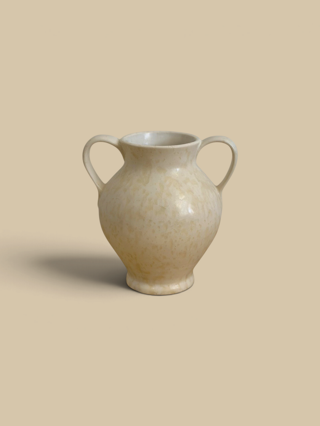 Homestyle Collective cream stoneware vase with double handles and subtle spatter glaze finish on a rustic table.