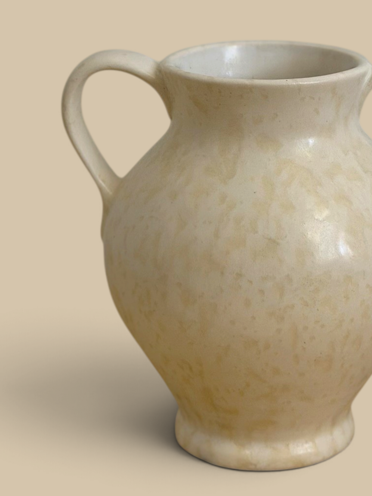 Homestyle Collective cream stoneware vase with double handles and subtle spatter glaze finish on a rustic table.