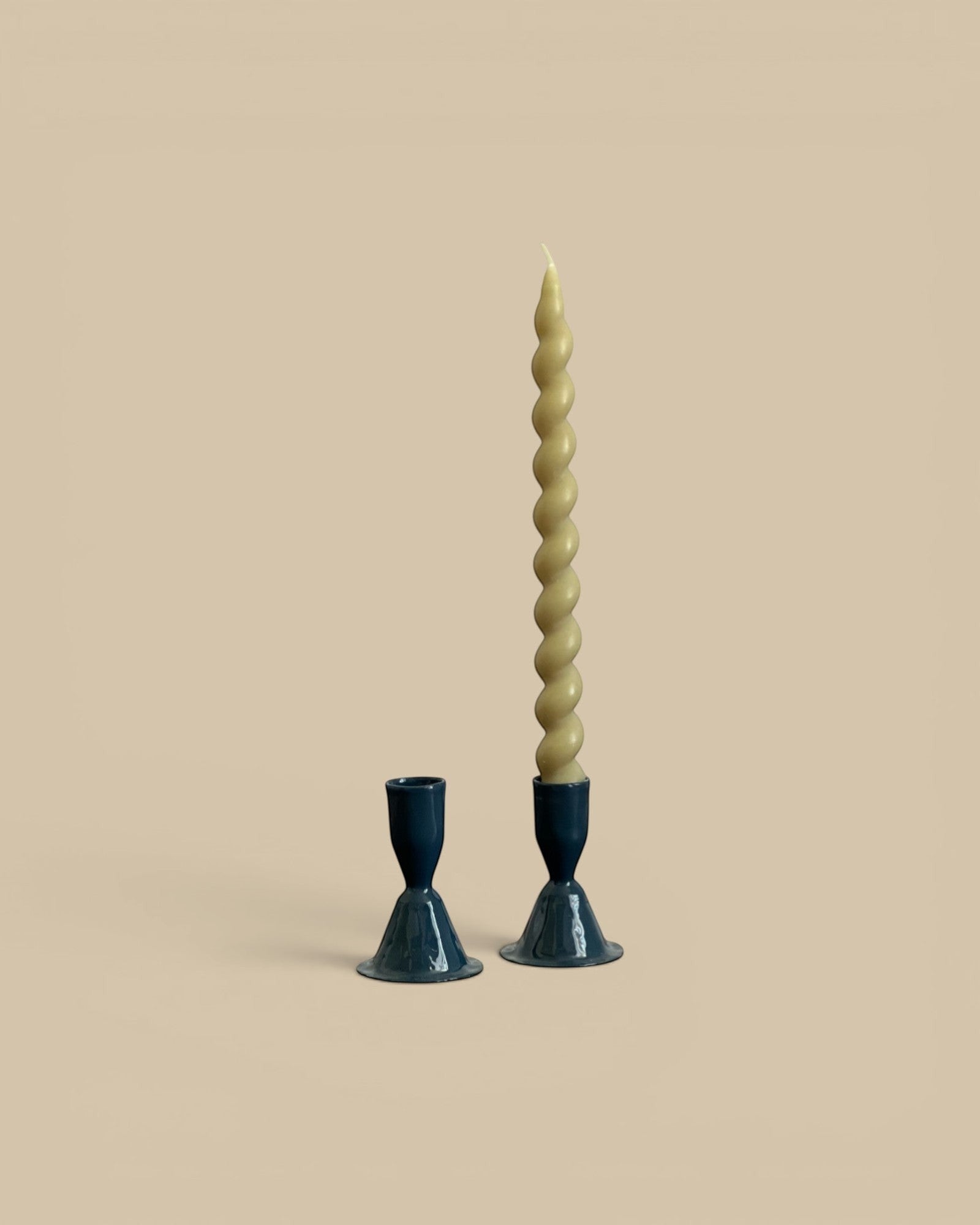 Homestyle Collective hand-forged dark blue metal candlestick holders, one small and one medium, with a tall twisted candle.