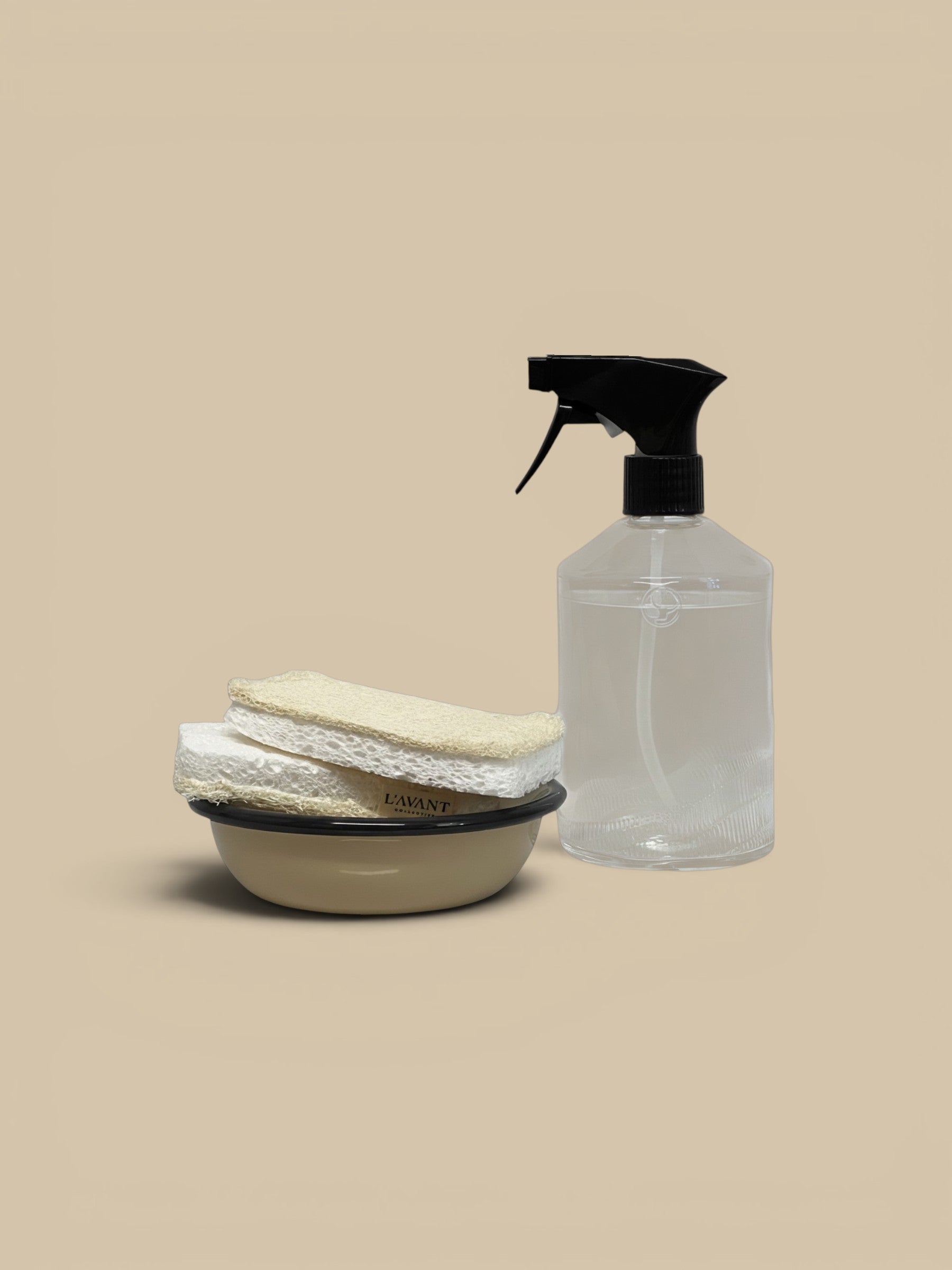 Homestyle Collective L'avant eco-friendly loofah and cellulose sponges in a beige bowl with a clear spray bottle.