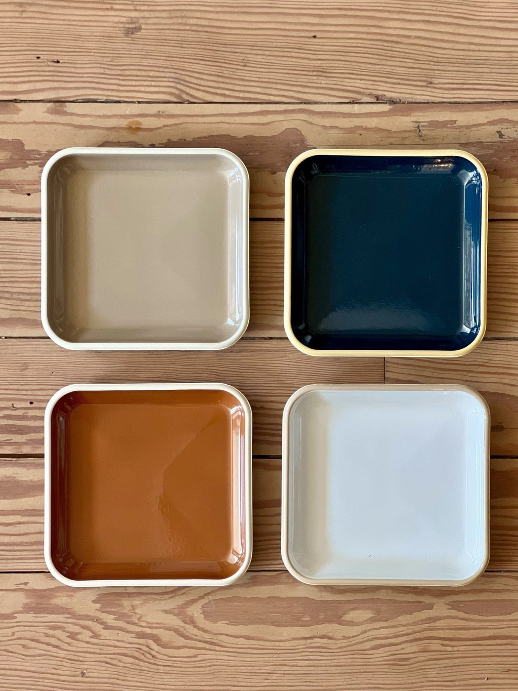 Homestyle Collective set of 4 square 8" enamel plates in tan, navy, rust, and white with cream rims.