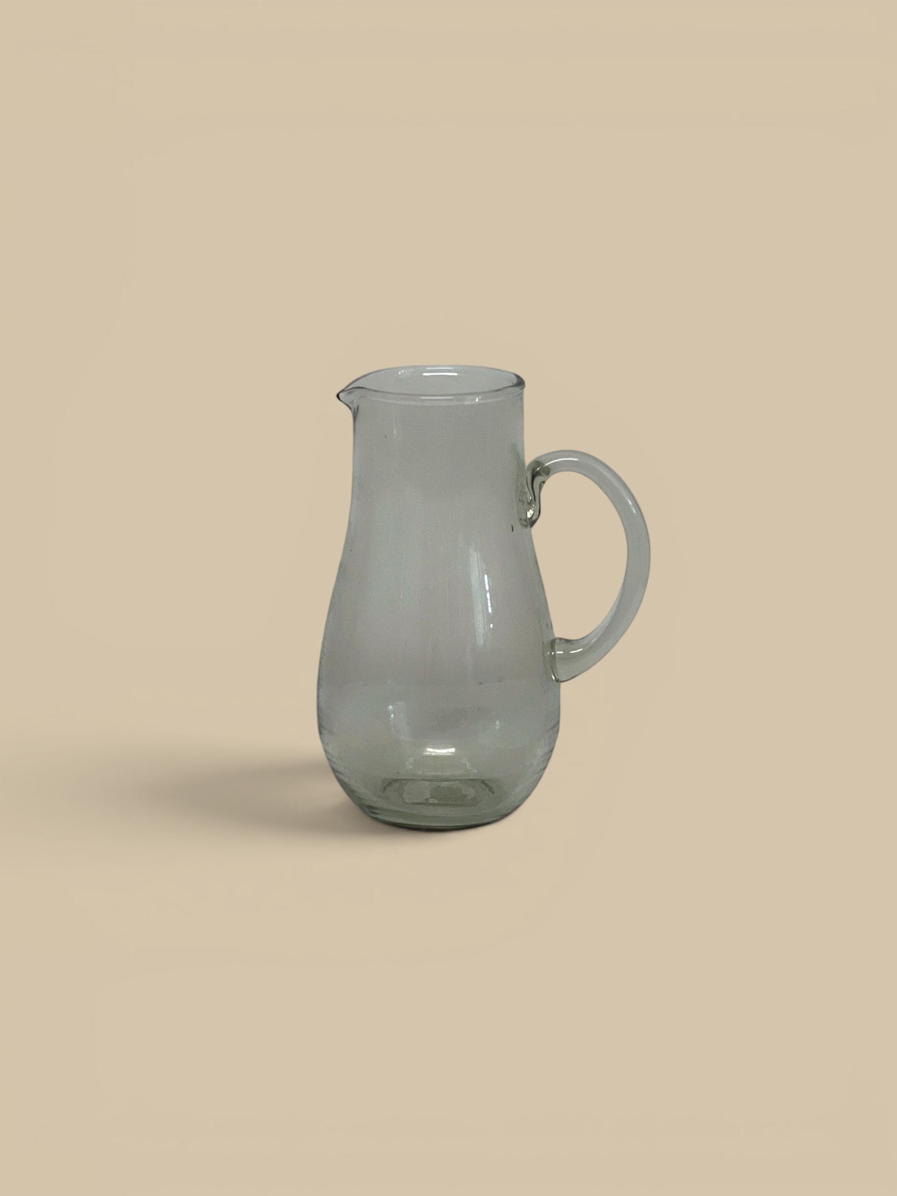 Homestyle Collective Ferra glass pitcher, clear, handcrafted with a sculptural silhouette and handle. Perfect for serving beverages.